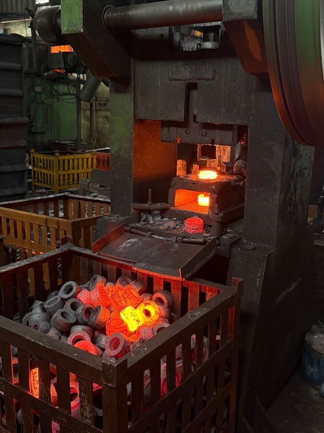 Basket of freshly forged parts beside the press