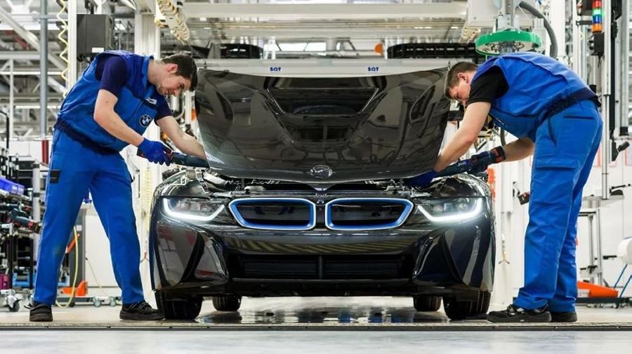 Technicians working on a car on an assembly line